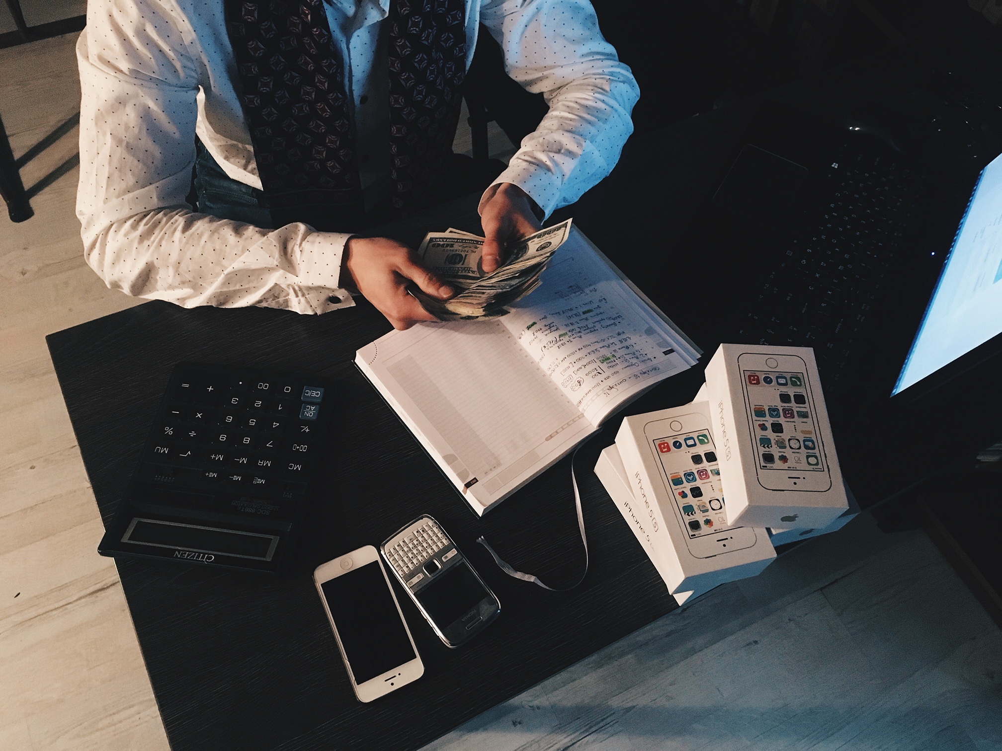 Canva - Person Counting Money With Smartphones in Front on Desk